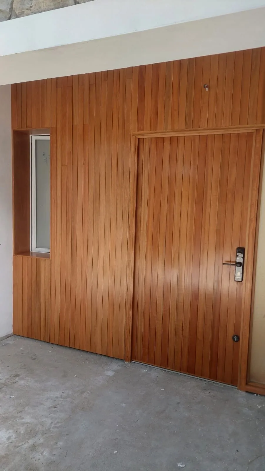 Pared revestida en tablas de madera con la puerta integrada al revestimiento