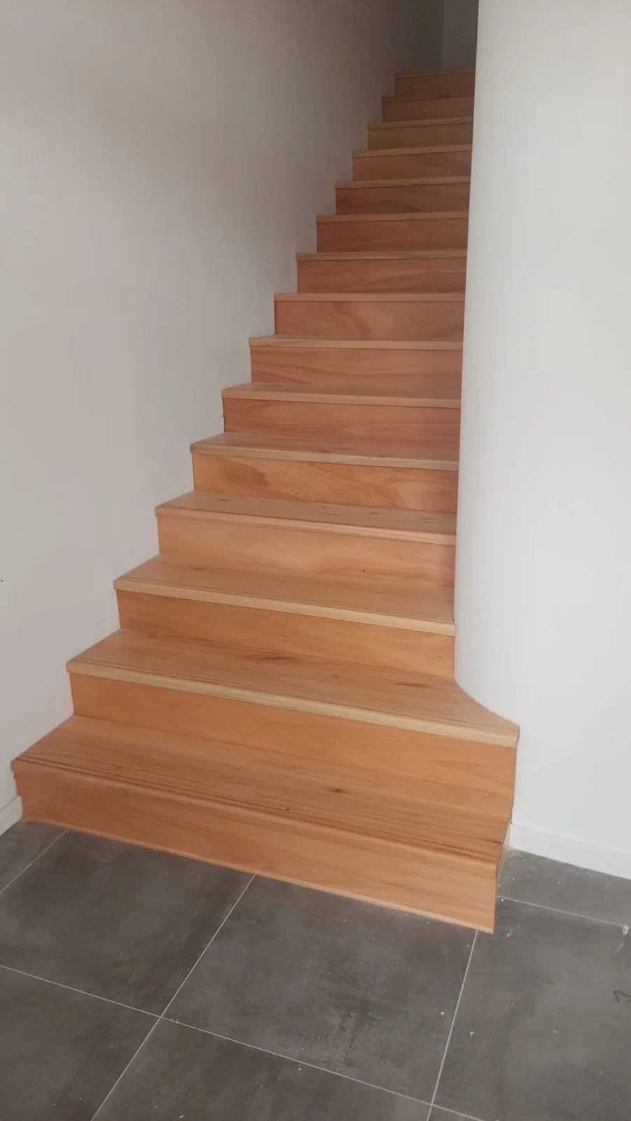 Escalera revestida en madera clara, peldaño por peldaño