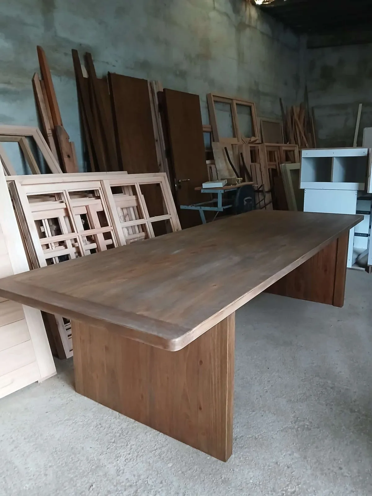 Mesa larga de madera maciza con patas de placa, en el taller