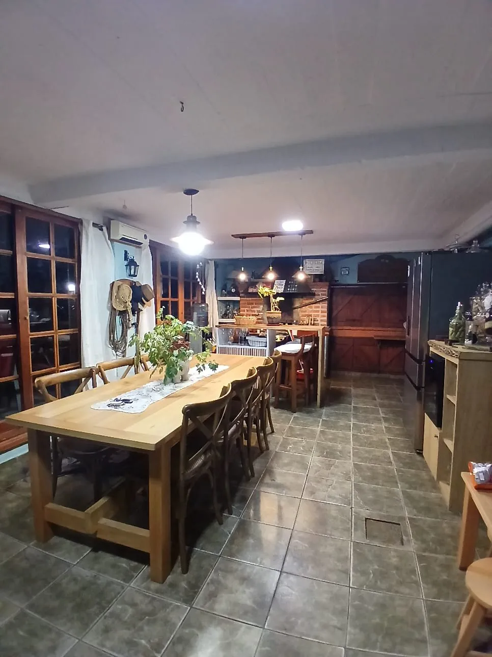 Comedor con mesa larga de madera y sillas, en un quincho
