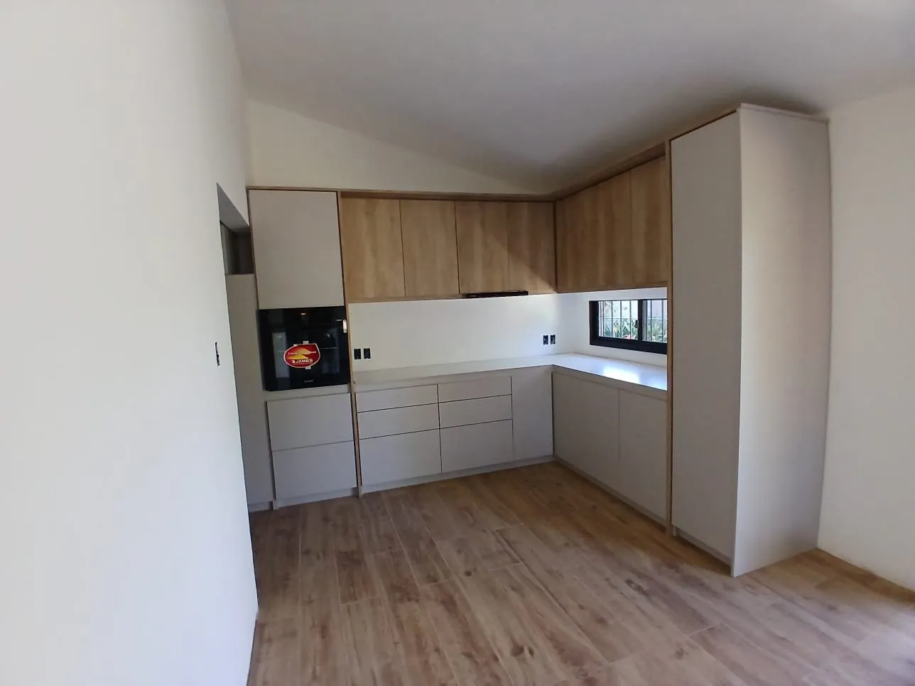 Cocina en L con bajomesadas blancos y alacenas de madera
