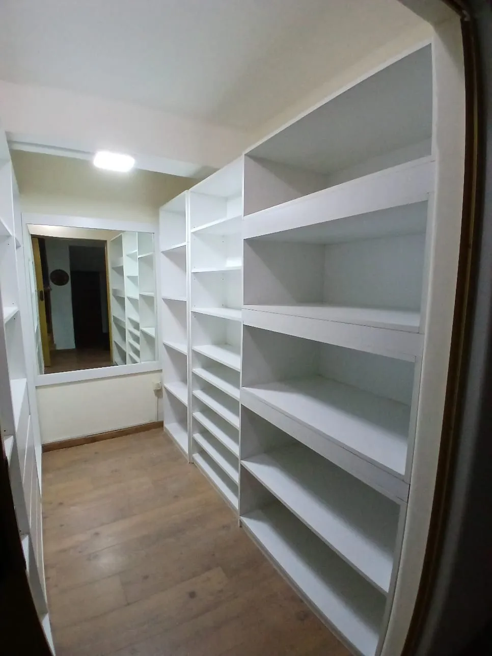 Vestidor con estanterías blancas de piso a techo