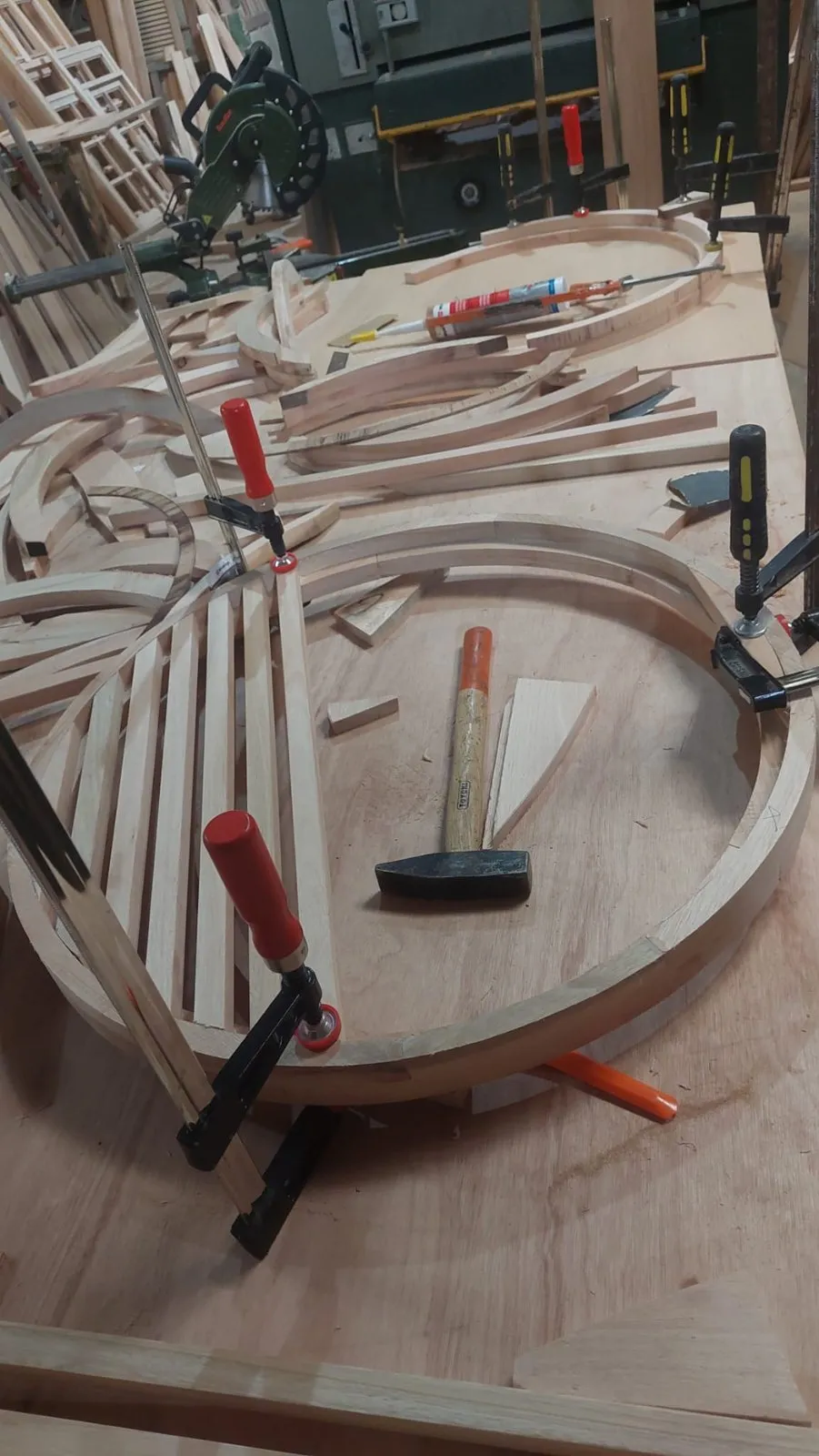 Pieza curva de madera en el banco de trabajo, sujeta con sargentos mientras se arma